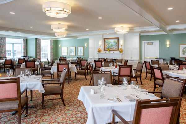 Elegant dining room in an independent living community featuring table service seating, natural light, and residential-style finishes.