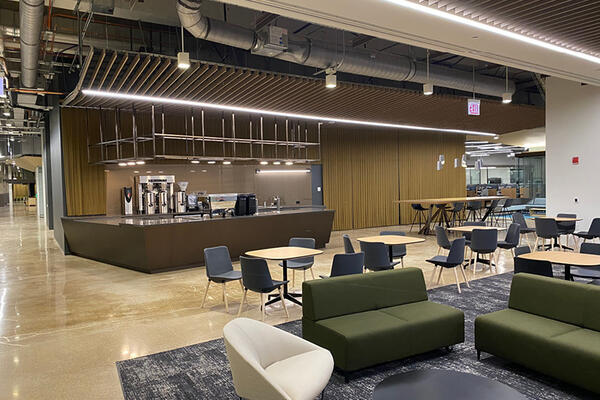 A coffee bar in the lobby features a wood ceiling, custom light fixture and cabinetry, with coiled metal drapery in the backdrop.